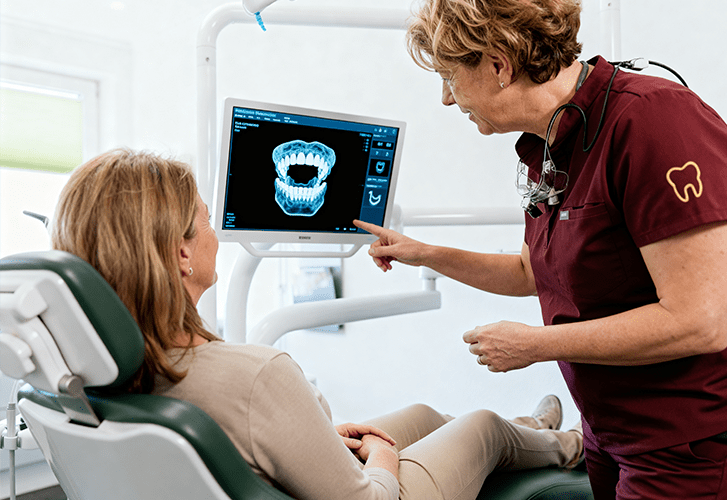 Zahnärztin erklärt einer Patientin die digitale 3D-Planung der Aligner-Zahnschiene am Monitor.